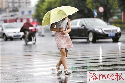 在九都路与解放路交叉口,一名女子撑着伞在风雨中艰难前行  记者